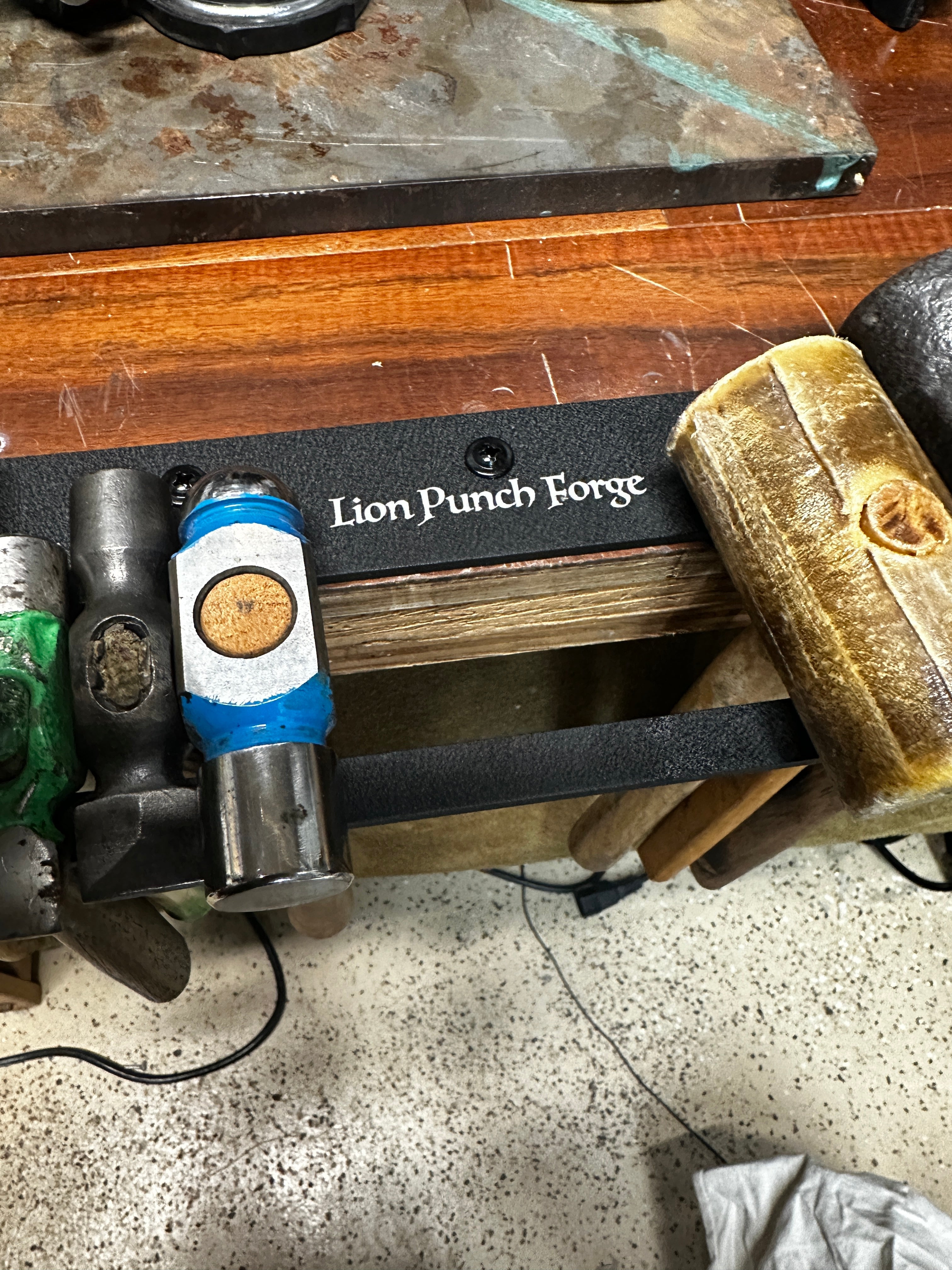 Tool with 'Lion Punch Forge' branding on a workbench.
