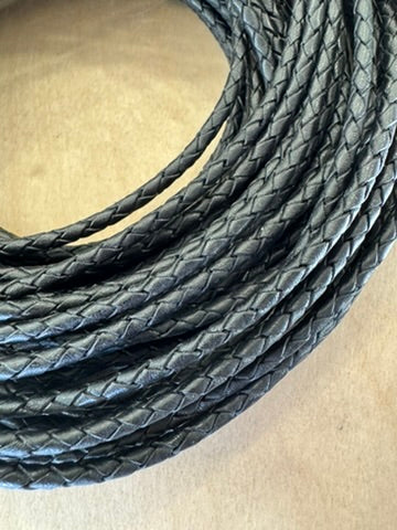 A black, machine-braided leather bolo cord with plastic tips.