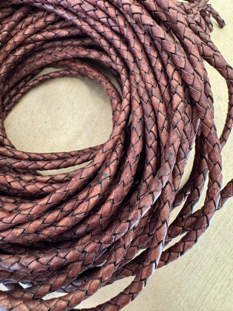 A brown, machine-braided leather bolo cord with plastic tips