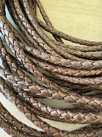 A chocolate brown, machine-braided leather bolo cord with plastic tips.