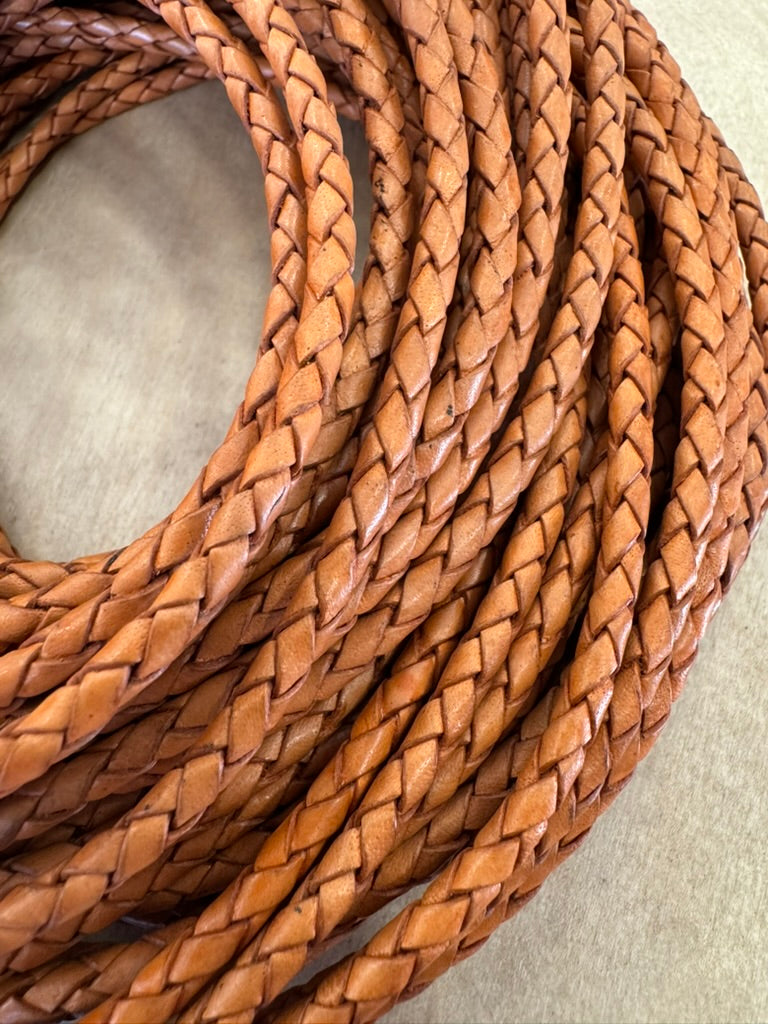 A mustard, machine-braided leather bolo cord with plastic tips.