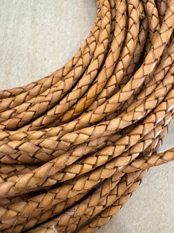 A tan, machine-braided leather bolo cord with plastic tips.